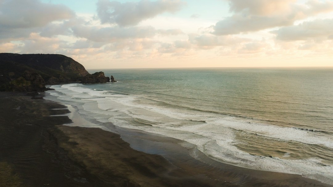 Aerial drone view of a turquoise coastline with waves and cliffs at golden hour