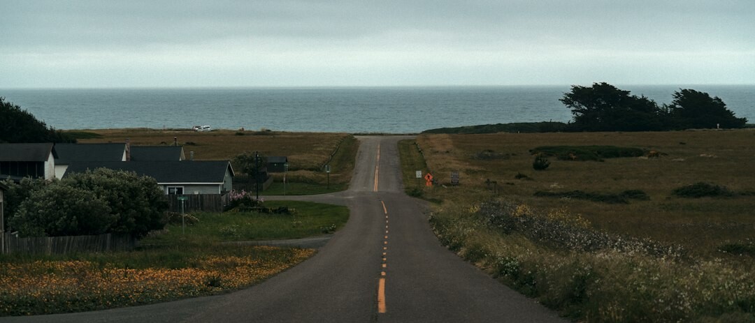 Rural countryside road leading toward modern architecture near the coast